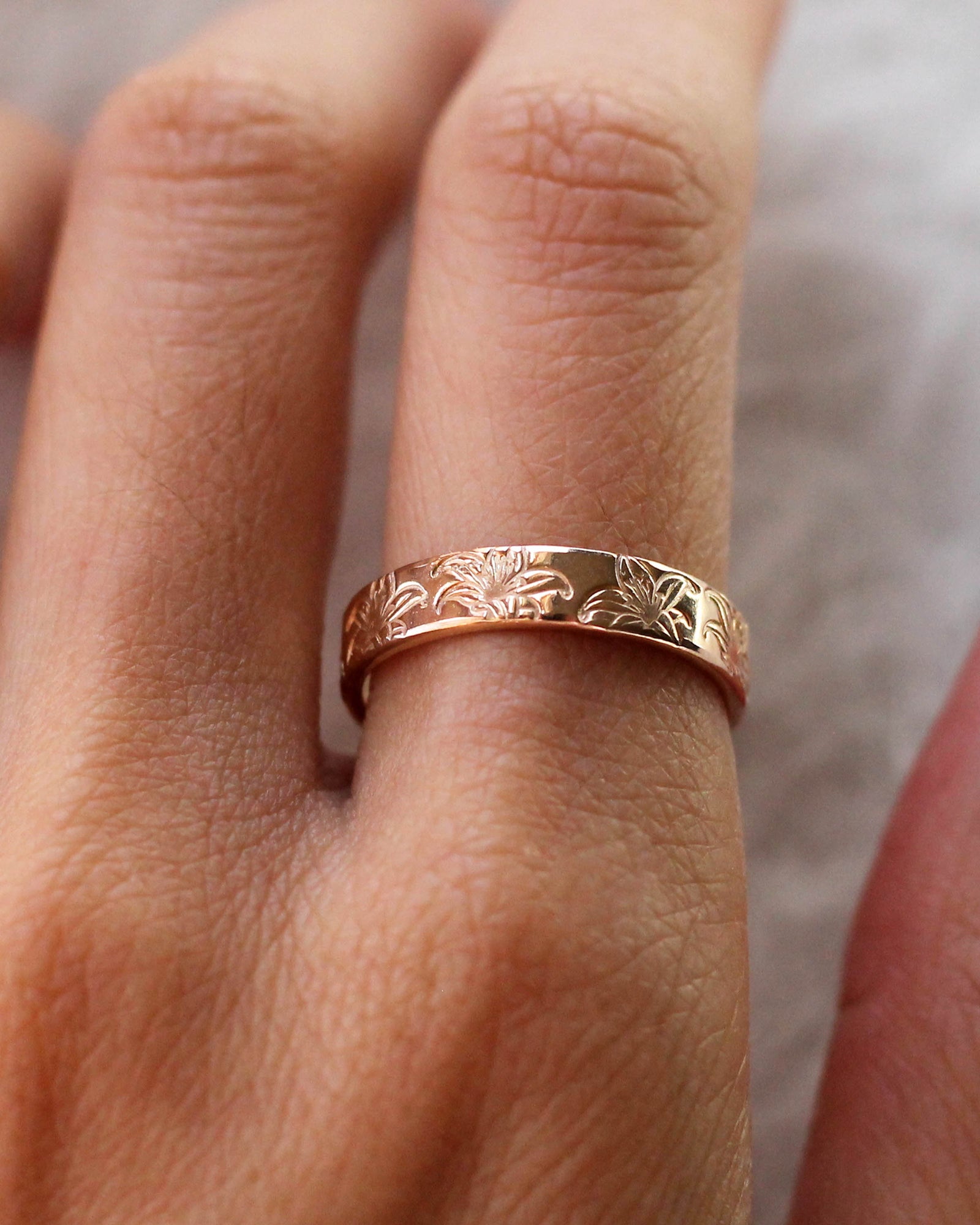 A gold filled band ring with hand stamped lily flowers.
