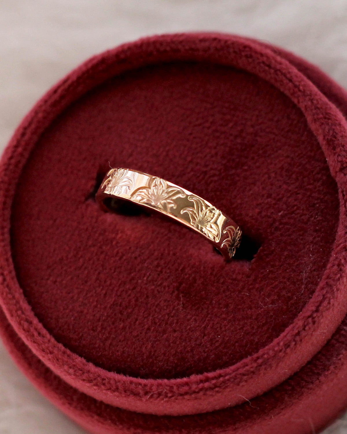 A gold filled band ring with hand stamped lily flowers.