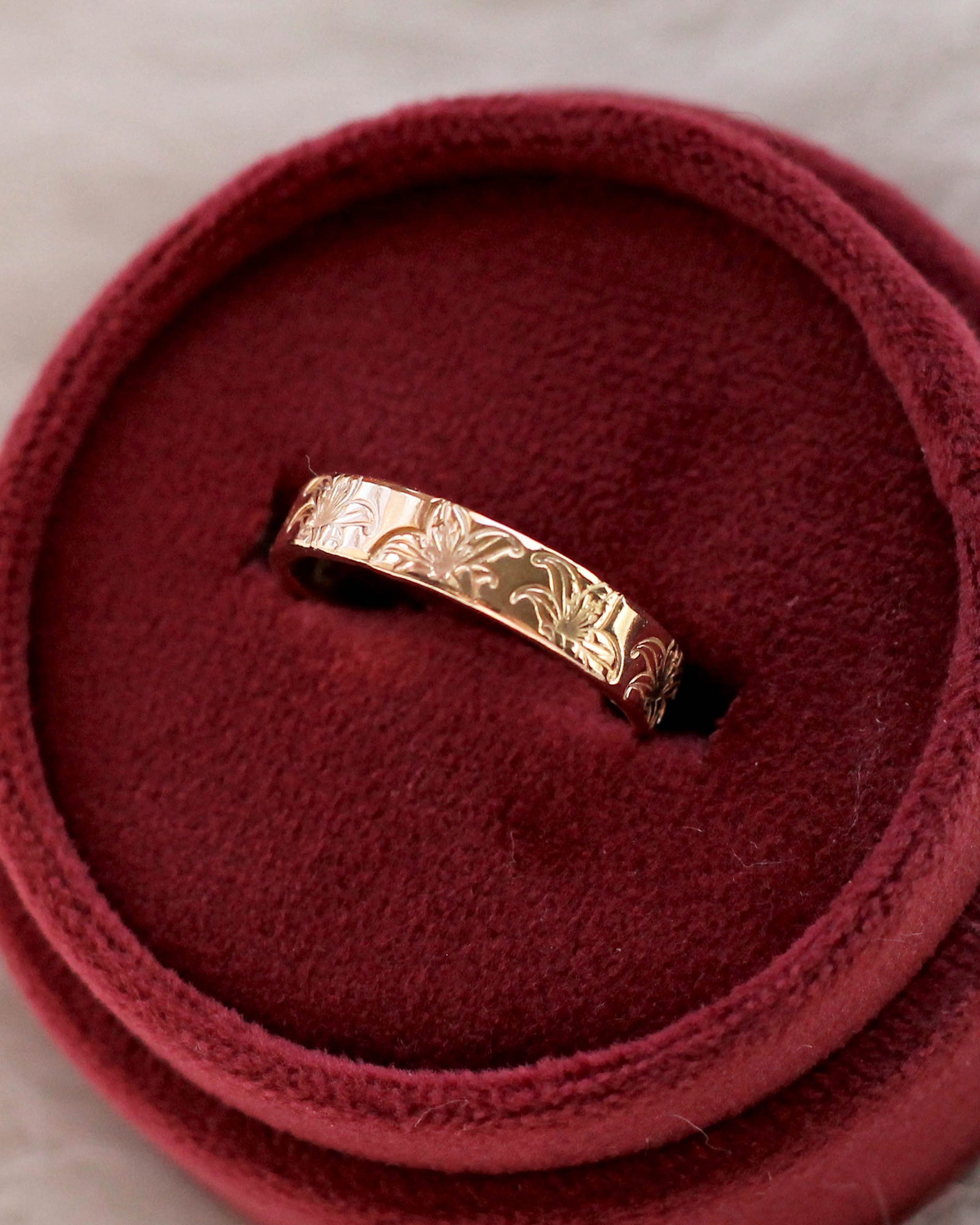 A gold filled band ring with hand stamped lily flowers.